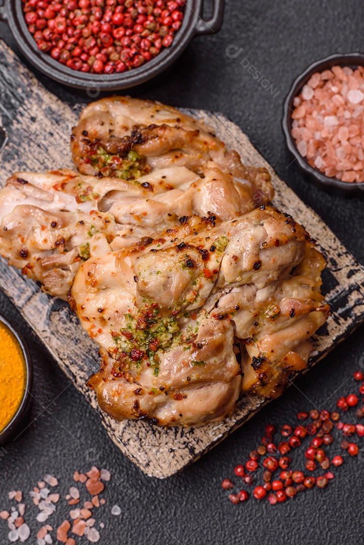 A imagem mostra sobrecoxas de frango grelhadas, servidas em um prato escuro com temperos