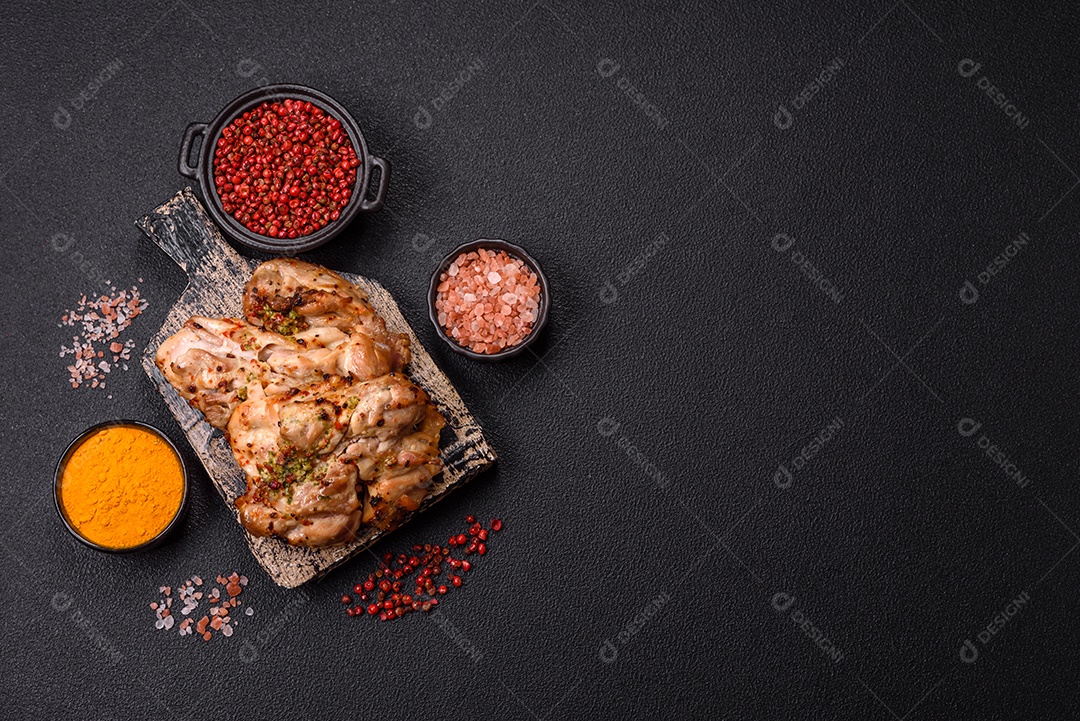 A imagem mostra sobrecoxas de frango grelhadas, servidas em um prato escuro com temperos