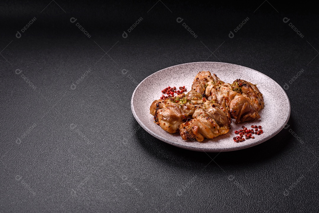 A imagem mostra sobrecoxas de frango grelhadas, servidas em um prato escuro com temperos