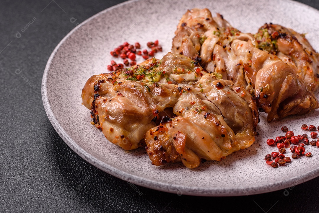 A imagem mostra sobrecoxas de frango grelhadas, servidas em um prato escuro com temperos