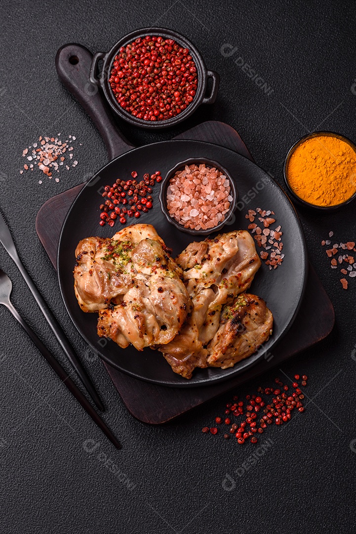 A imagem mostra sobrecoxas de frango grelhadas, servidas em um prato escuro com temperos
