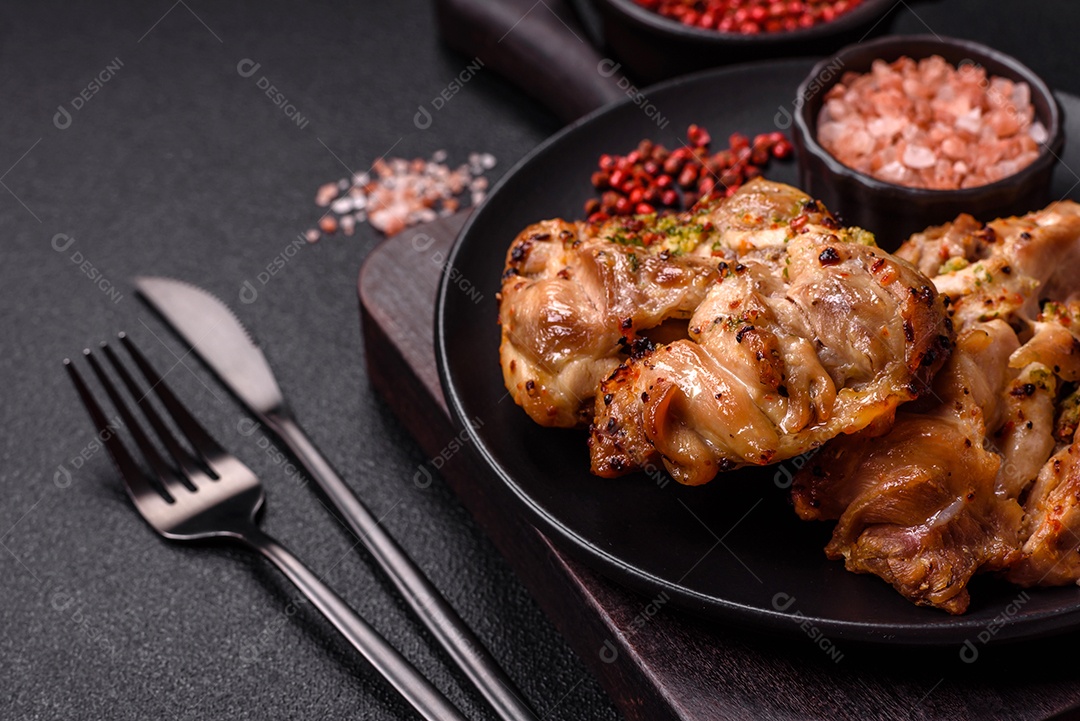 A imagem mostra sobrecoxas de frango grelhadas, servidas em um prato escuro com temperos