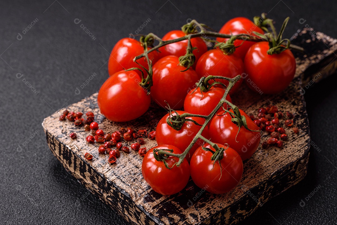 A imagem mostra tomates-cereja em um cacho, que são pequenos e redondos, frequentemente usados em saladas, espetinhos e canapés.