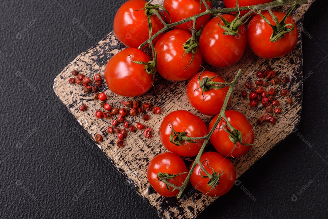A imagem mostra tomates cereja em rama, acompanhados de pimenta rosa em grãos, sal rosa do Himalaia e açafrão em pó