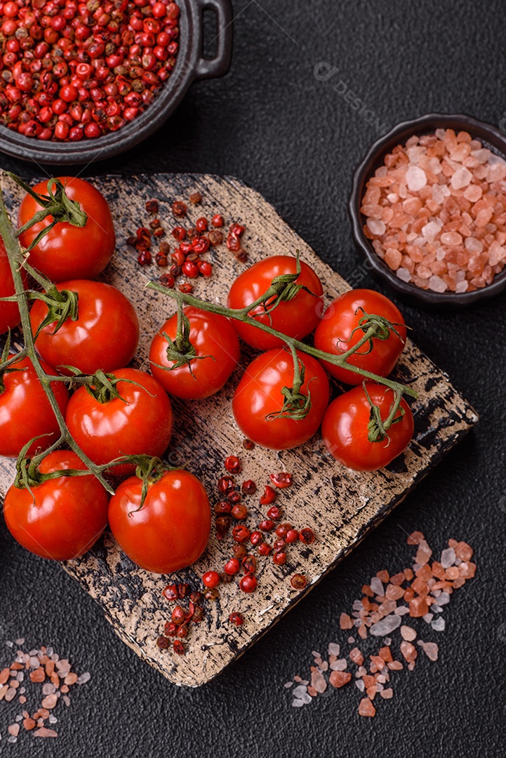 A imagem mostra tomates cereja em rama, acompanhados de pimenta rosa em grãos, sal rosa do Himalaia e açafrão em pó