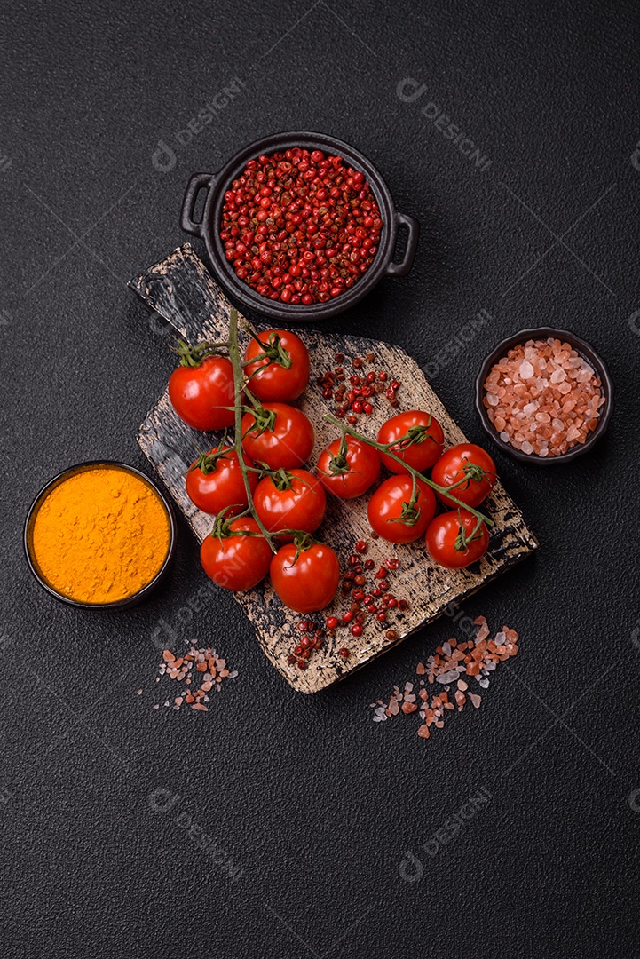 A imagem mostra tomates cereja em rama, acompanhados de pimenta rosa em grãos, sal rosa do Himalaia e açafrão em pó