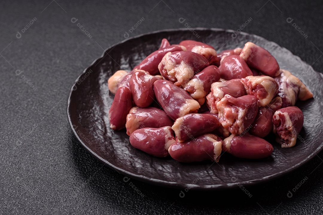 A imagem mostra corações de frango crus em uma tábua de madeira, acompanhados de pimenta rosa e tomates-cereja.