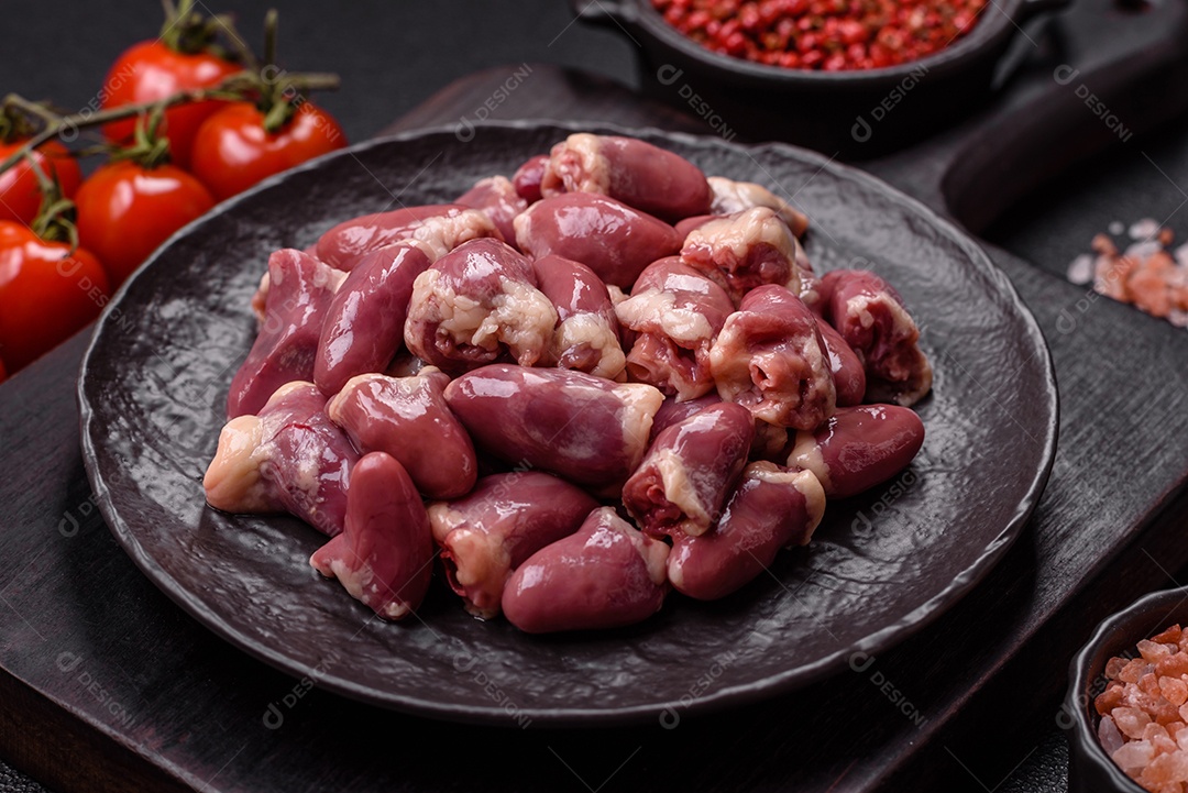 A imagem mostra corações de frango crus em uma tábua de madeira, acompanhados de pimenta rosa e tomates-cereja.