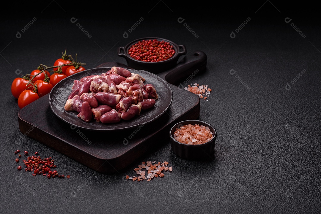 A imagem mostra corações de frango crus em uma tábua de madeira, acompanhados de pimenta rosa e tomates-cereja.