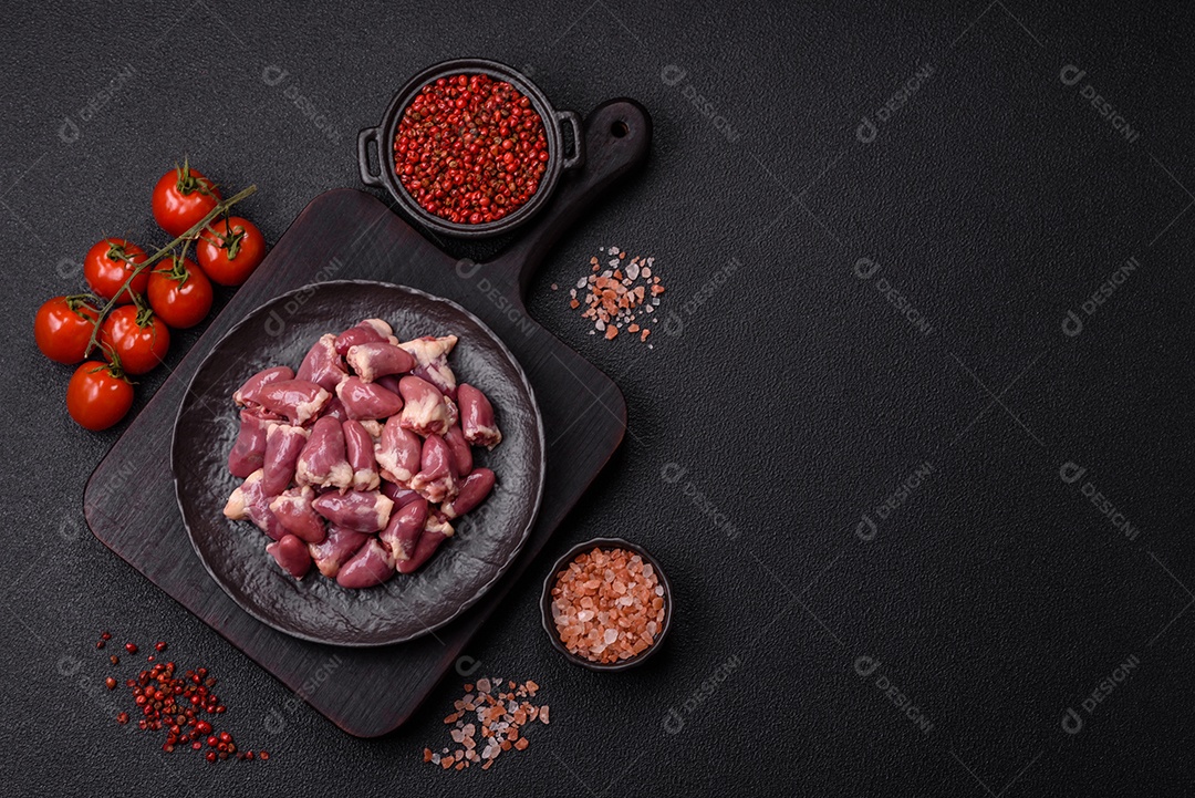 A imagem mostra corações de frango crus em uma tábua de madeira, acompanhados de pimenta rosa e tomates-cereja.