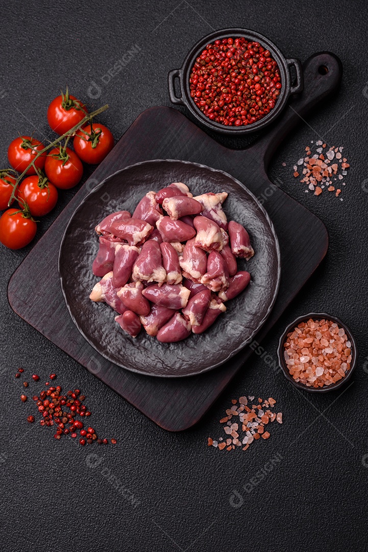 A imagem mostra corações de frango crus em uma tábua de madeira, acompanhados de pimenta rosa e tomates-cereja.