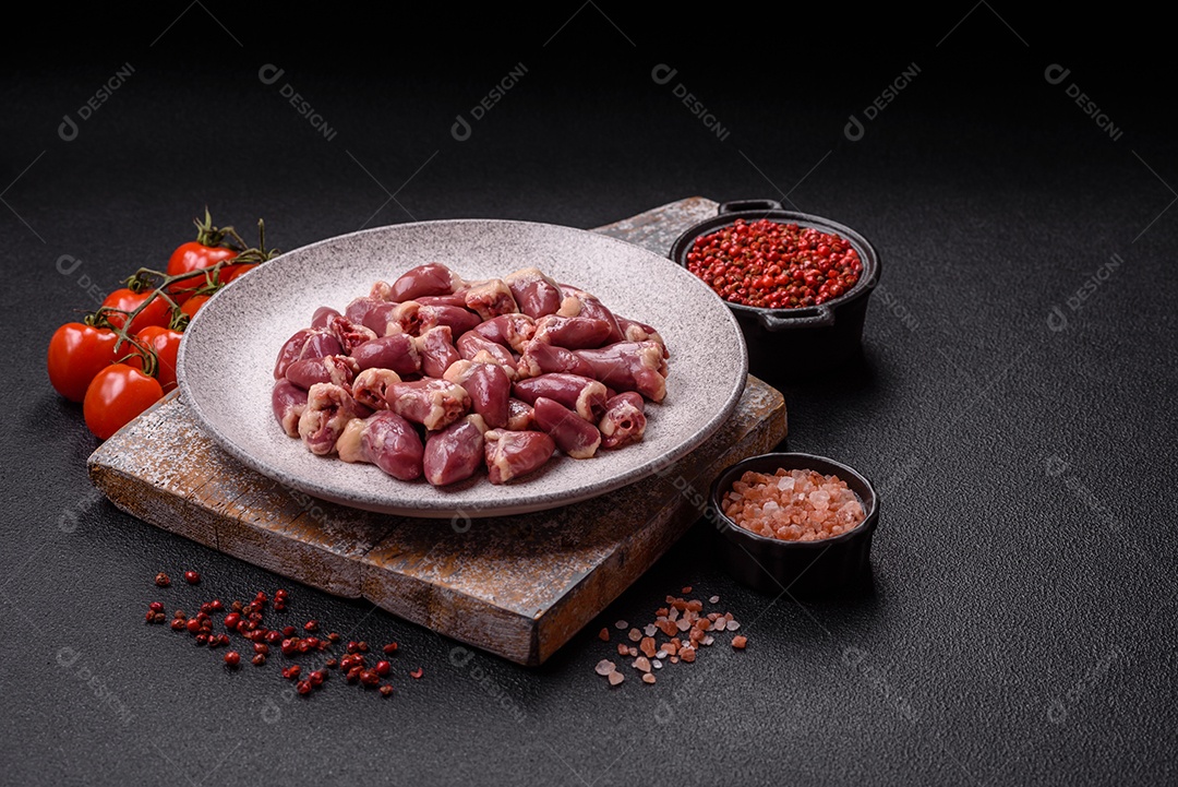 A imagem mostra corações de frango crus em uma tábua de madeira, acompanhados de pimenta rosa e tomates-cereja.