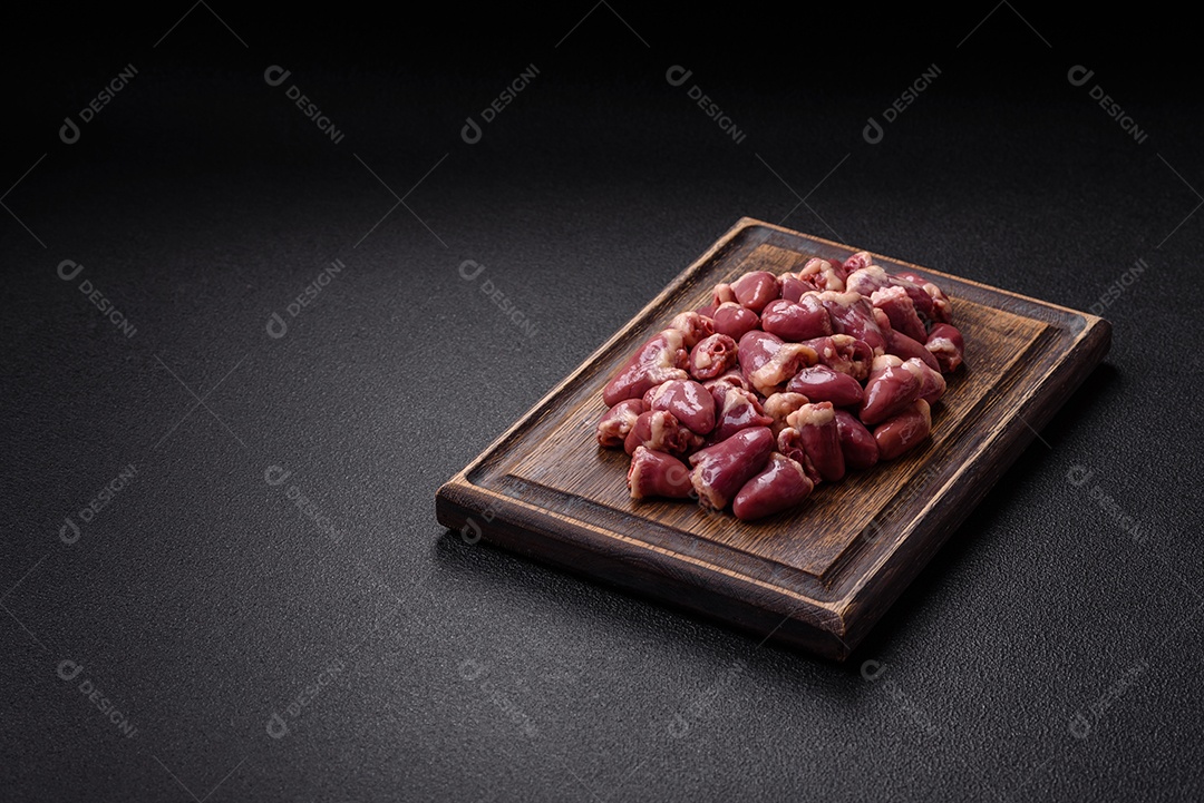 A imagem mostra corações de frango crus em uma tábua de madeira, acompanhados de pimenta rosa e tomates-cereja.