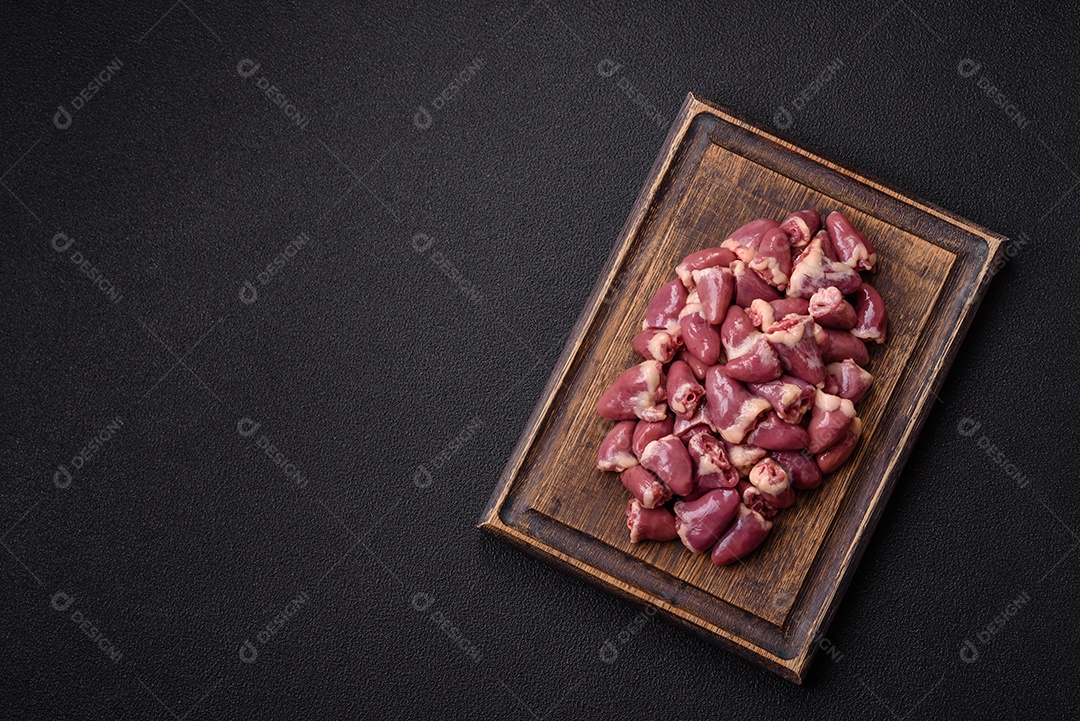 A imagem mostra corações de frango crus em uma tábua de madeira, acompanhados de pimenta rosa e tomates-cereja.