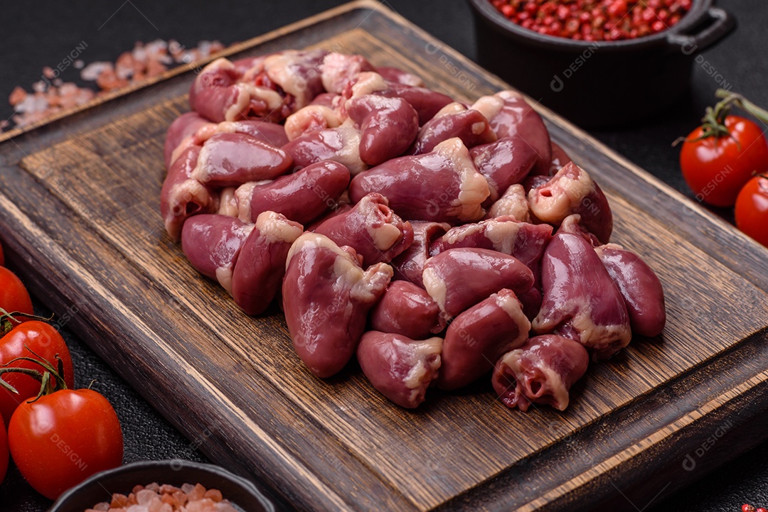 A imagem mostra corações de frango crus em uma tábua de madeira, acompanhados de pimenta rosa e tomates-cereja.