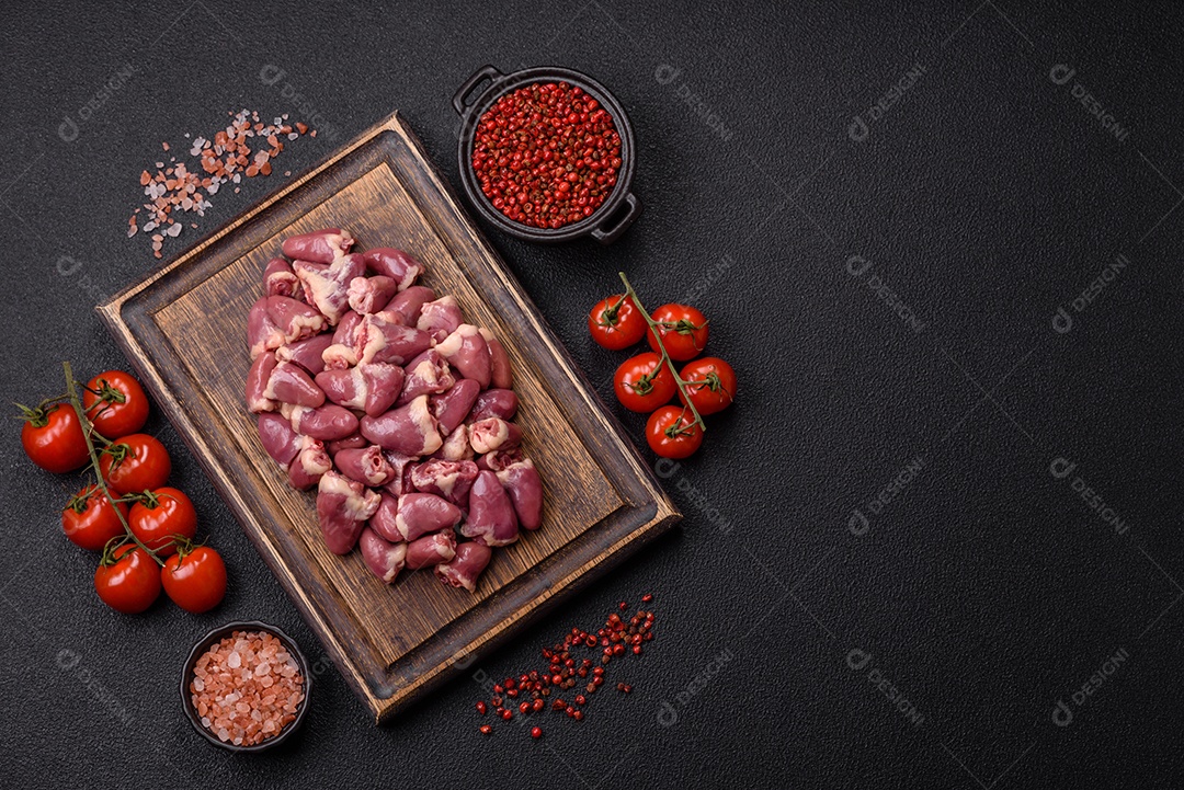 A imagem mostra corações de frango crus em uma tábua de madeira, acompanhados de pimenta rosa e tomates-cereja.