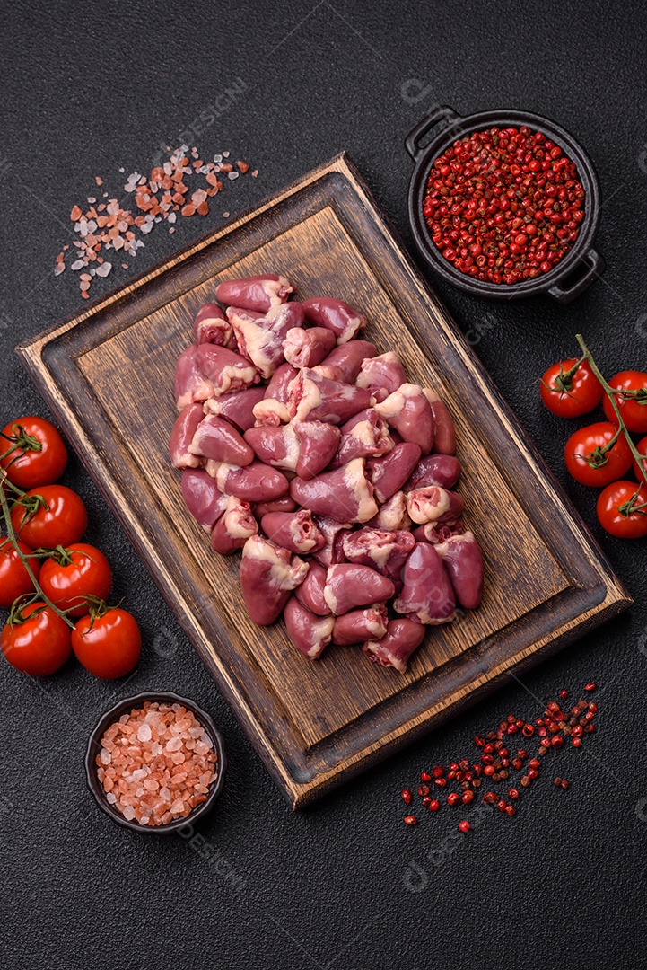 A imagem mostra corações de frango crus em uma tábua de madeira, acompanhados de pimenta rosa e tomates-cereja.