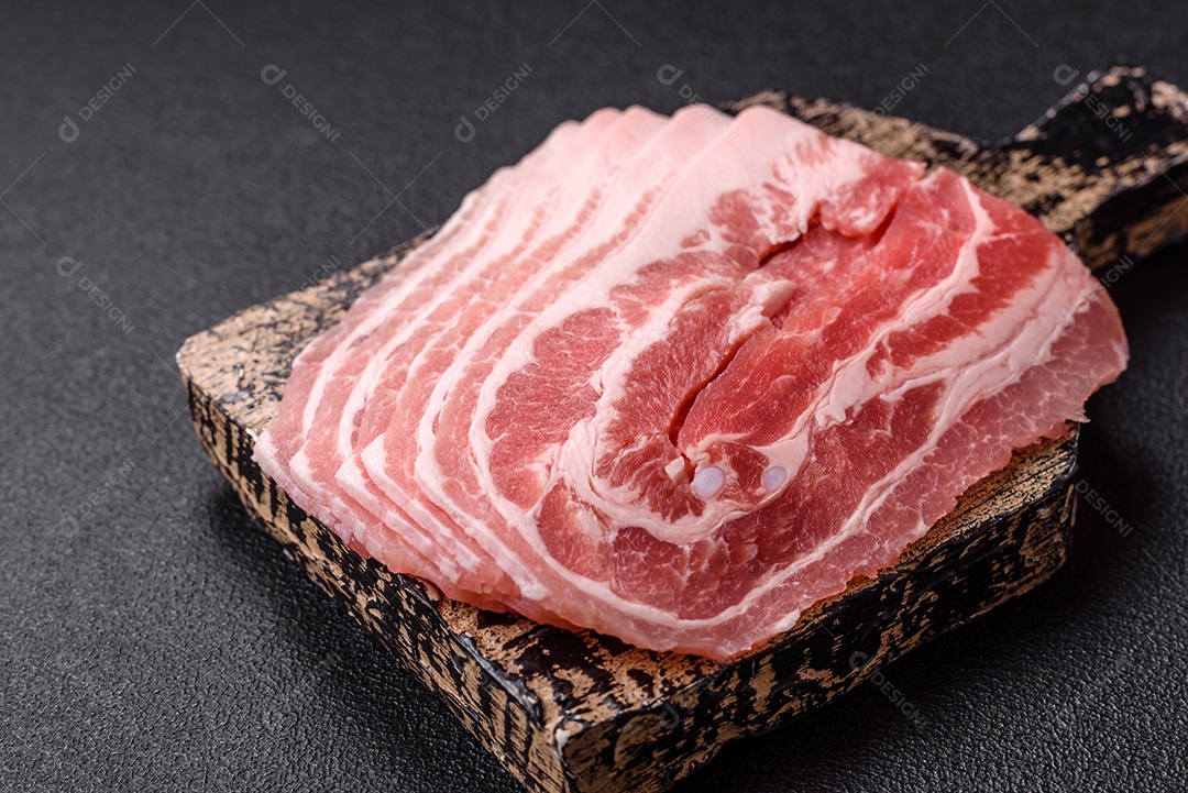 A imagem mostra fatias de barriga de porco crua, também conhecida como toucinho ou, em alguns casos, bacon. A barriga de porco