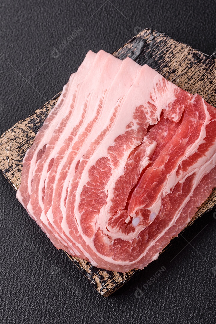 A imagem mostra fatias de barriga de porco crua, também conhecida como toucinho ou, em alguns casos, bacon. A barriga de porco