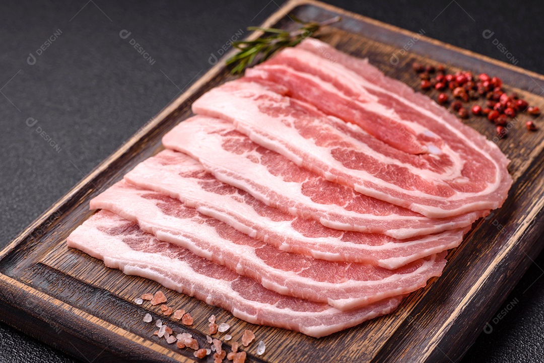 A imagem mostra fatias de barriga de porco crua, também conhecida como toucinho ou, em alguns casos, bacon. A barriga de porco