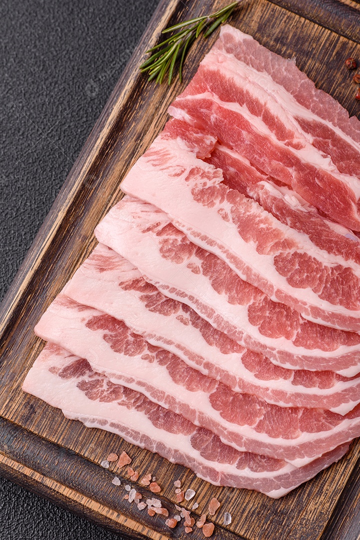 A imagem mostra fatias de barriga de porco crua, também conhecida como toucinho ou, em alguns casos, bacon. A barriga de porco