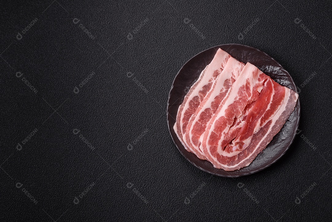 A imagem mostra fatias de barriga de porco crua, também conhecida como toucinho ou, em alguns casos, bacon. A barriga de porco
