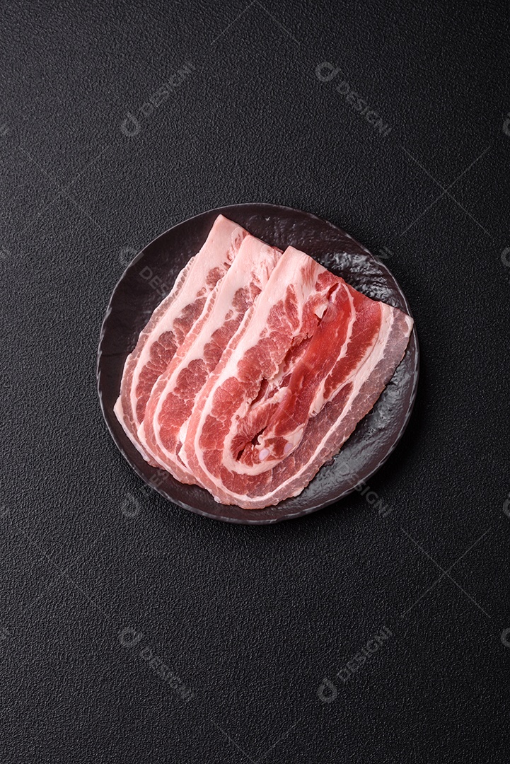 A imagem mostra fatias de barriga de porco crua, também conhecida como toucinho ou, em alguns casos, bacon. A barriga de porco