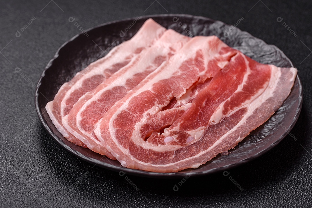 A imagem mostra fatias de barriga de porco crua, também conhecida como toucinho ou, em alguns casos, bacon. A barriga de porco