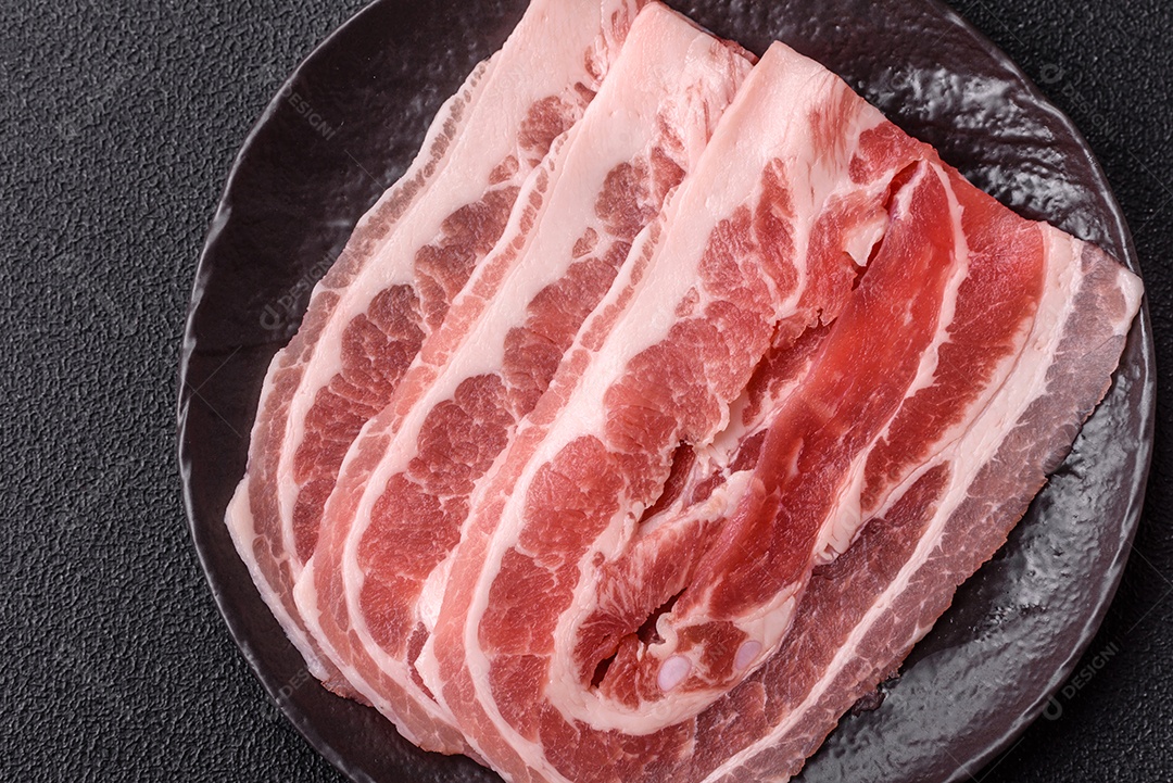 A imagem mostra fatias de barriga de porco crua, também conhecida como toucinho ou, em alguns casos, bacon. A barriga de porco