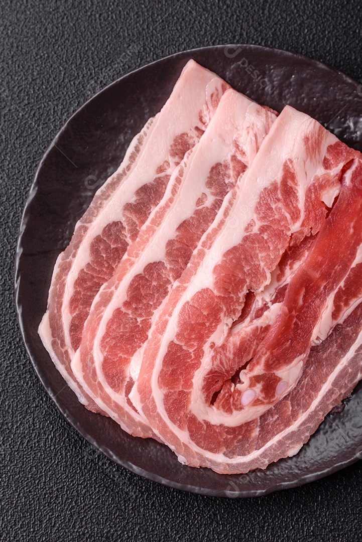 A imagem mostra fatias de barriga de porco crua, também conhecida como toucinho ou, em alguns casos, bacon. A barriga de porco