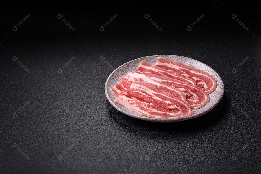 A imagem mostra fatias de barriga de porco crua, também conhecida como toucinho ou, em alguns casos, bacon. A barriga de porco