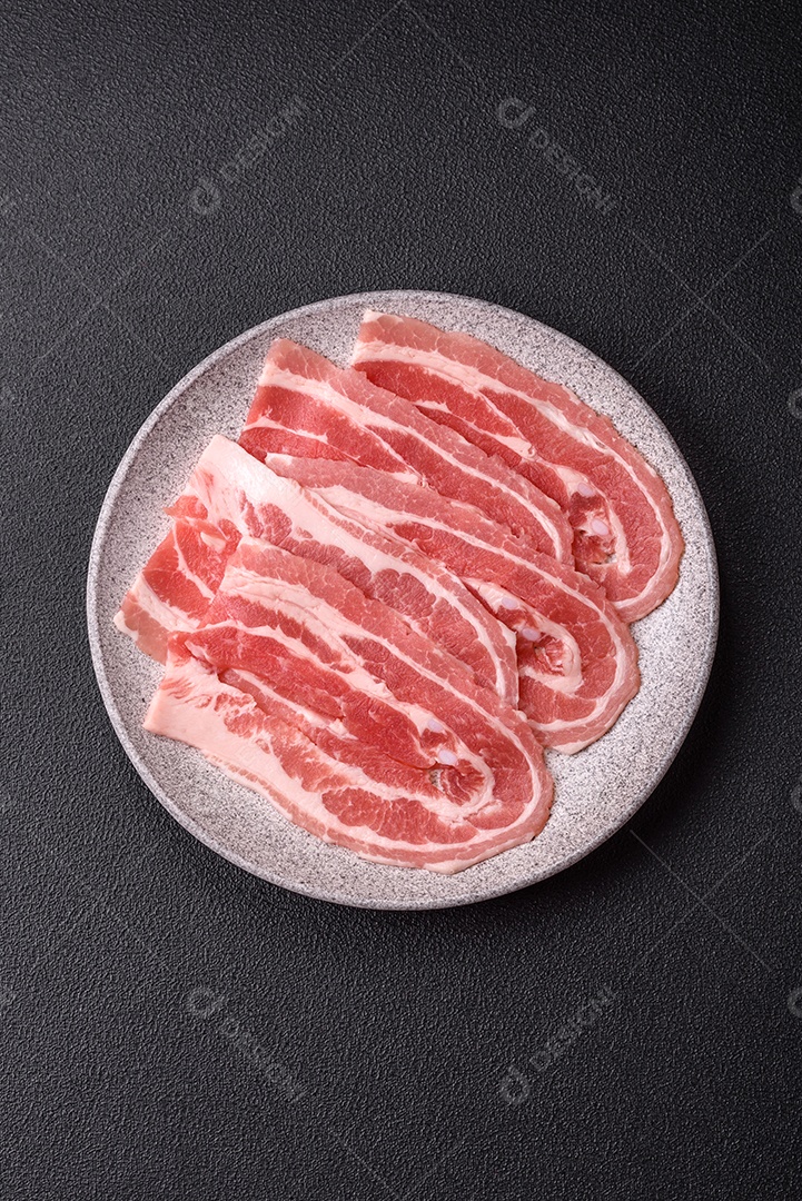 A imagem mostra fatias de barriga de porco crua, também conhecida como toucinho ou, em alguns casos, bacon. A barriga de porco