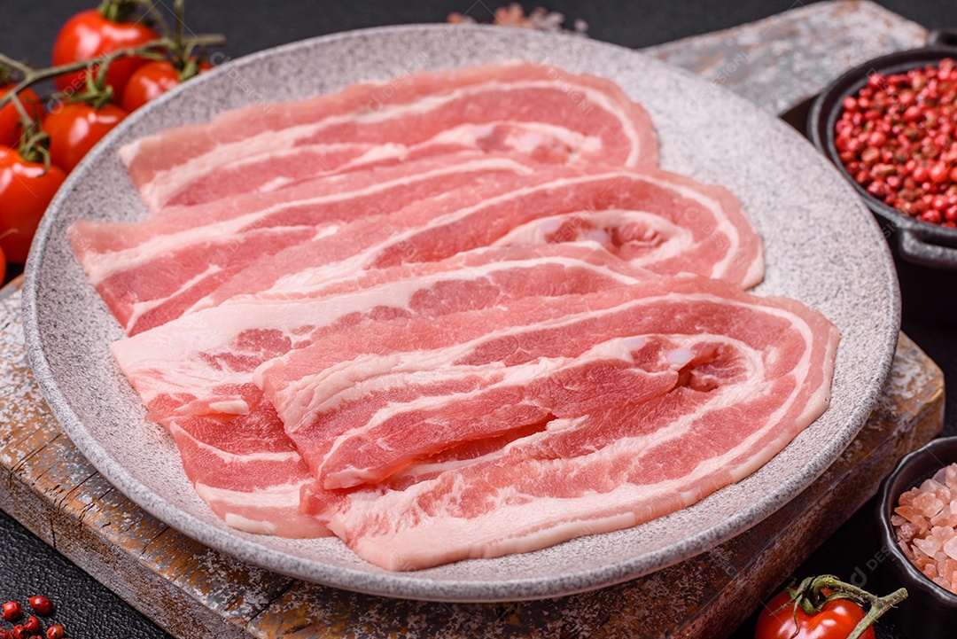 A imagem mostra fatias de barriga de porco crua, também conhecida como toucinho ou, em alguns casos, bacon. A barriga de porco