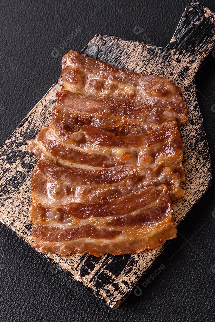 A imagem mostra toucinho frito em um prato, acompanhado de tomates-cereja e pimenta-rosa