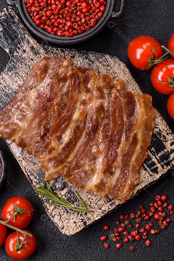 A imagem mostra toucinho frito em um prato, acompanhado de tomates-cereja e pimenta-rosa