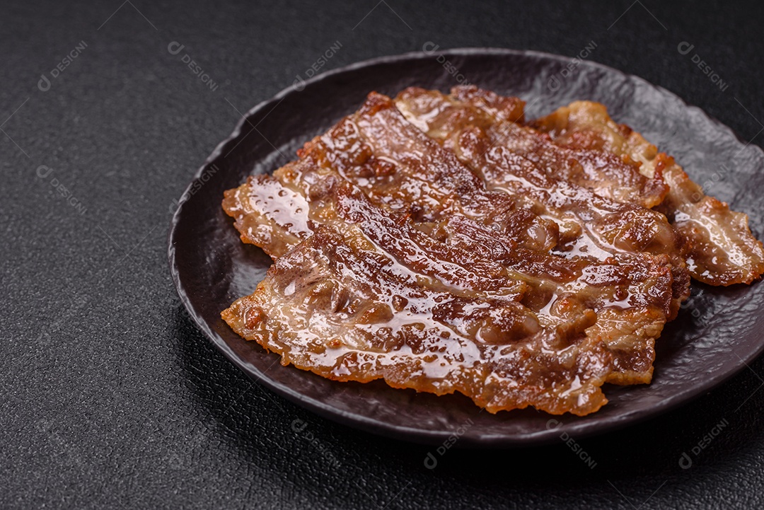 A imagem mostra toucinho frito em um prato, acompanhado de tomates-cereja e pimenta-rosa