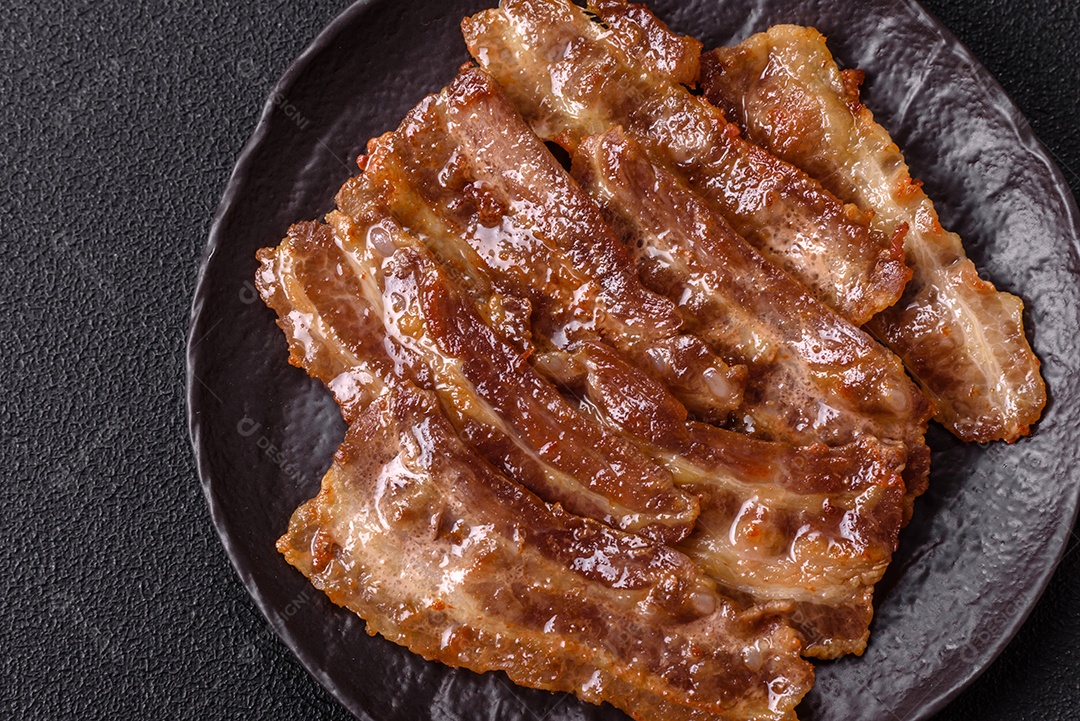 A imagem mostra toucinho frito em um prato, acompanhado de tomates-cereja e pimenta-rosa