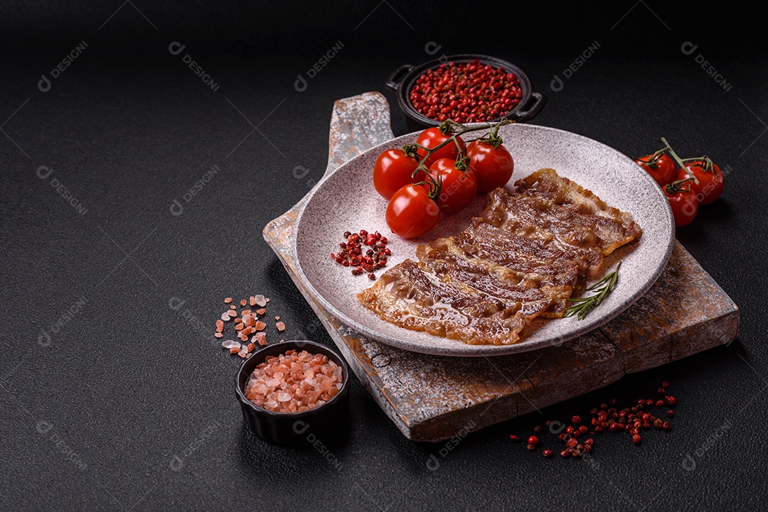 A imagem mostra toucinho frito em um prato, acompanhado de tomates-cereja e pimenta-rosa