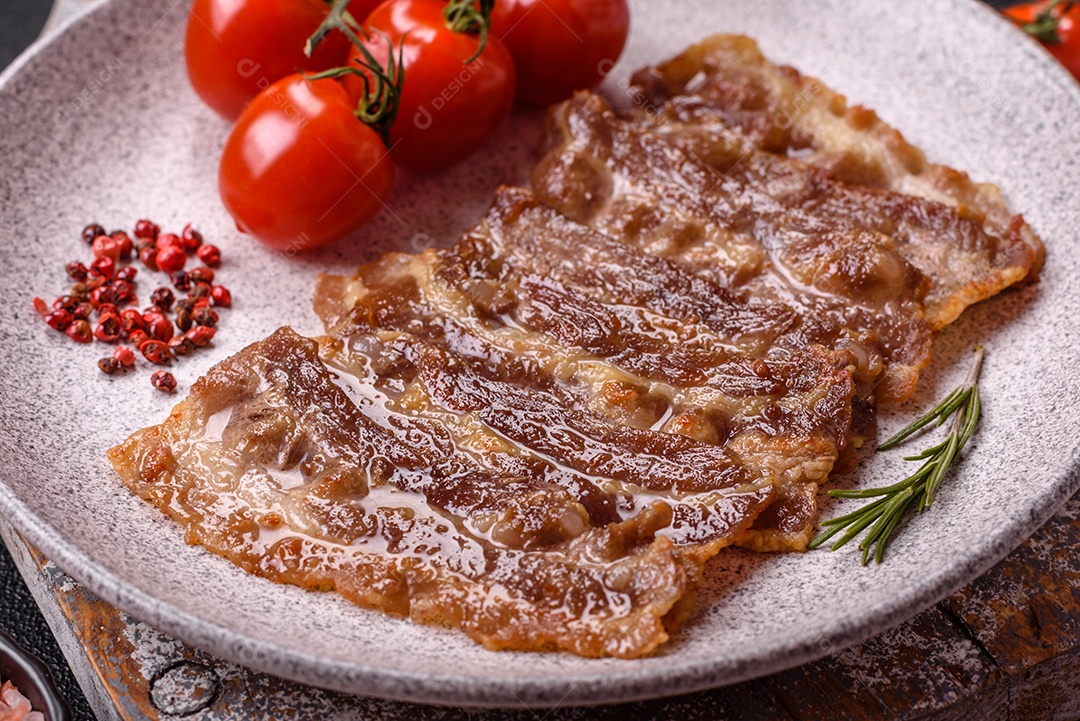 A imagem mostra toucinho frito em um prato, acompanhado de tomates-cereja e pimenta-rosa