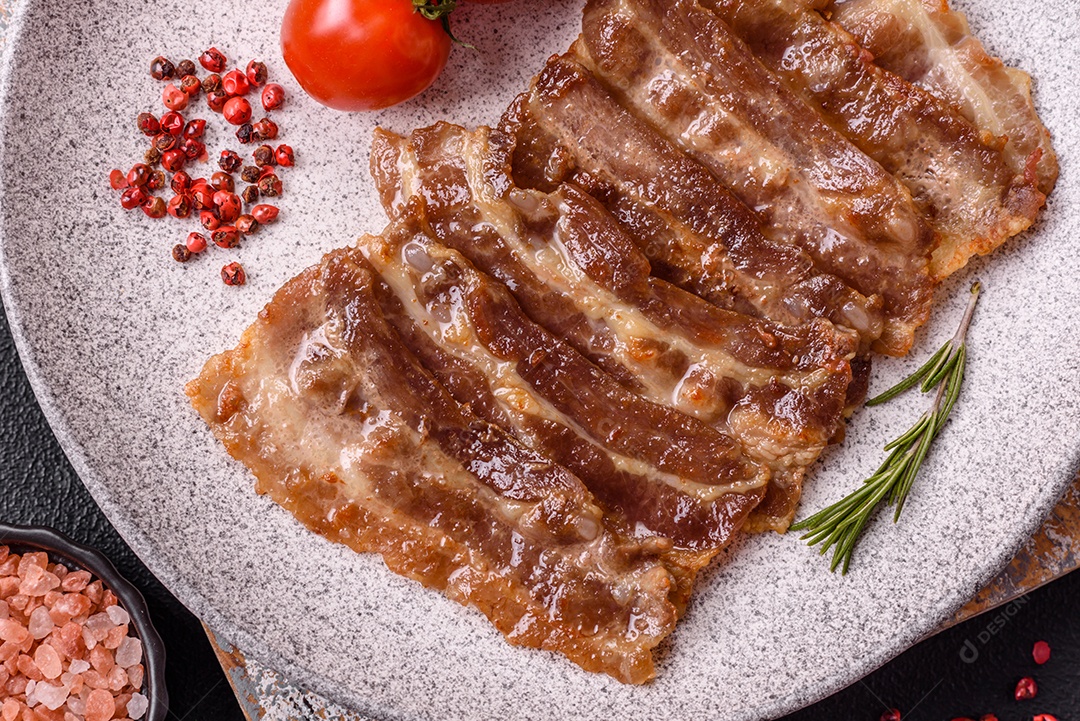 A imagem mostra toucinho frito em um prato, acompanhado de tomates-cereja e pimenta-rosa