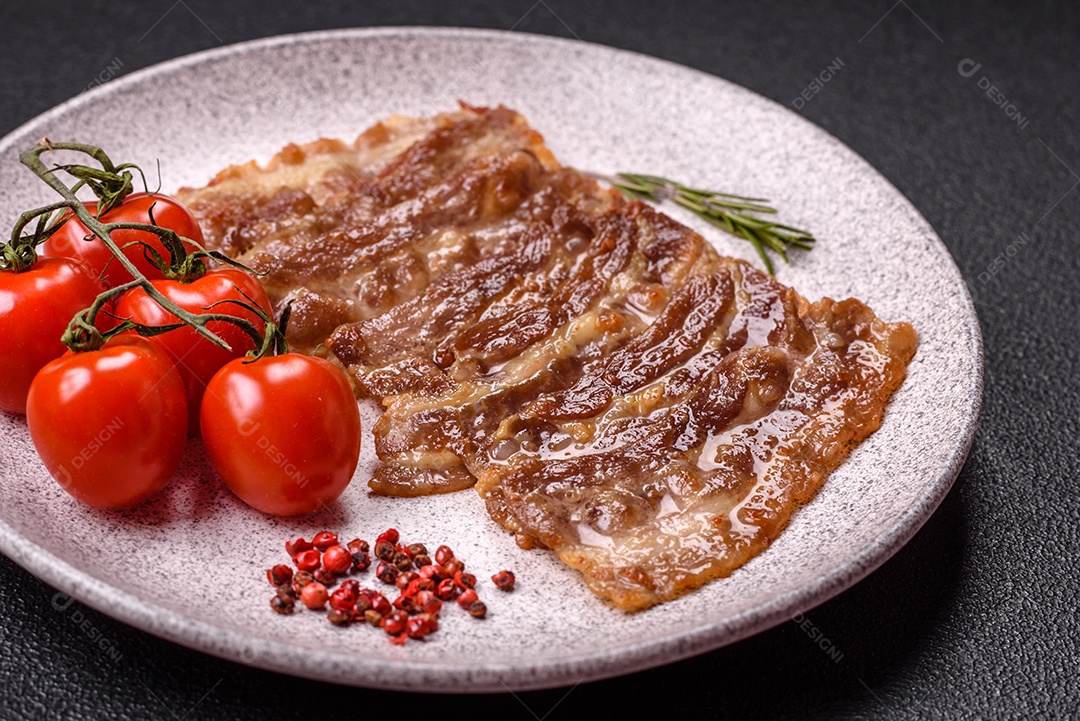 A imagem mostra toucinho frito em um prato, acompanhado de tomates-cereja e pimenta-rosa
