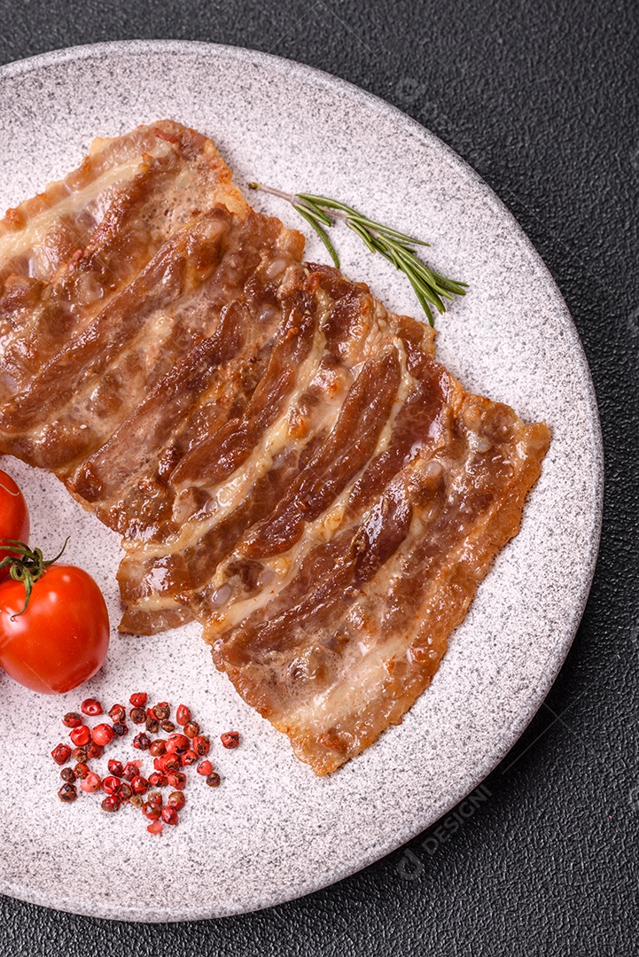 A imagem mostra toucinho frito em um prato, acompanhado de tomates-cereja e pimenta-rosa