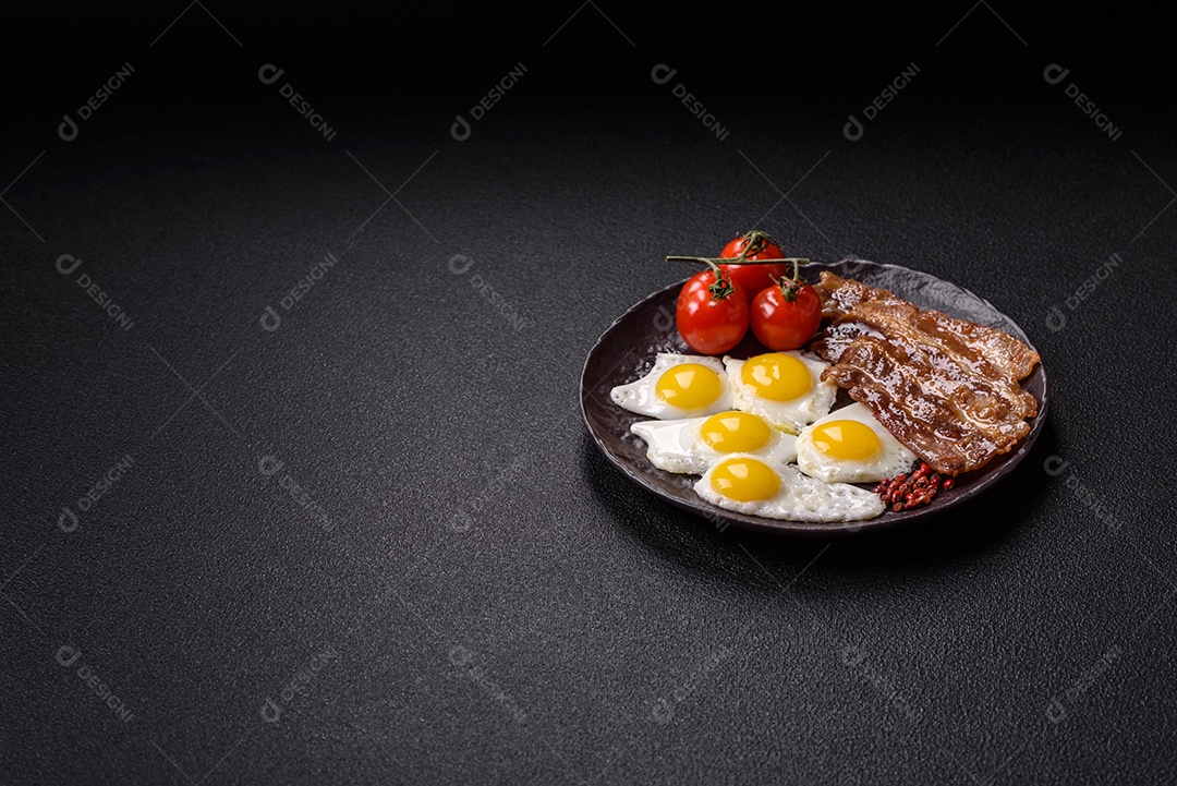 A imagem mostra um café da manhã farto com ovos fritos, bacon e tomates