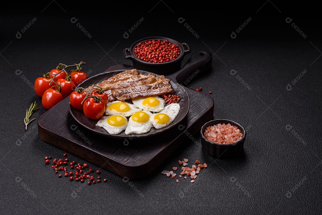 A imagem mostra um café da manhã farto com ovos fritos, bacon e tomates