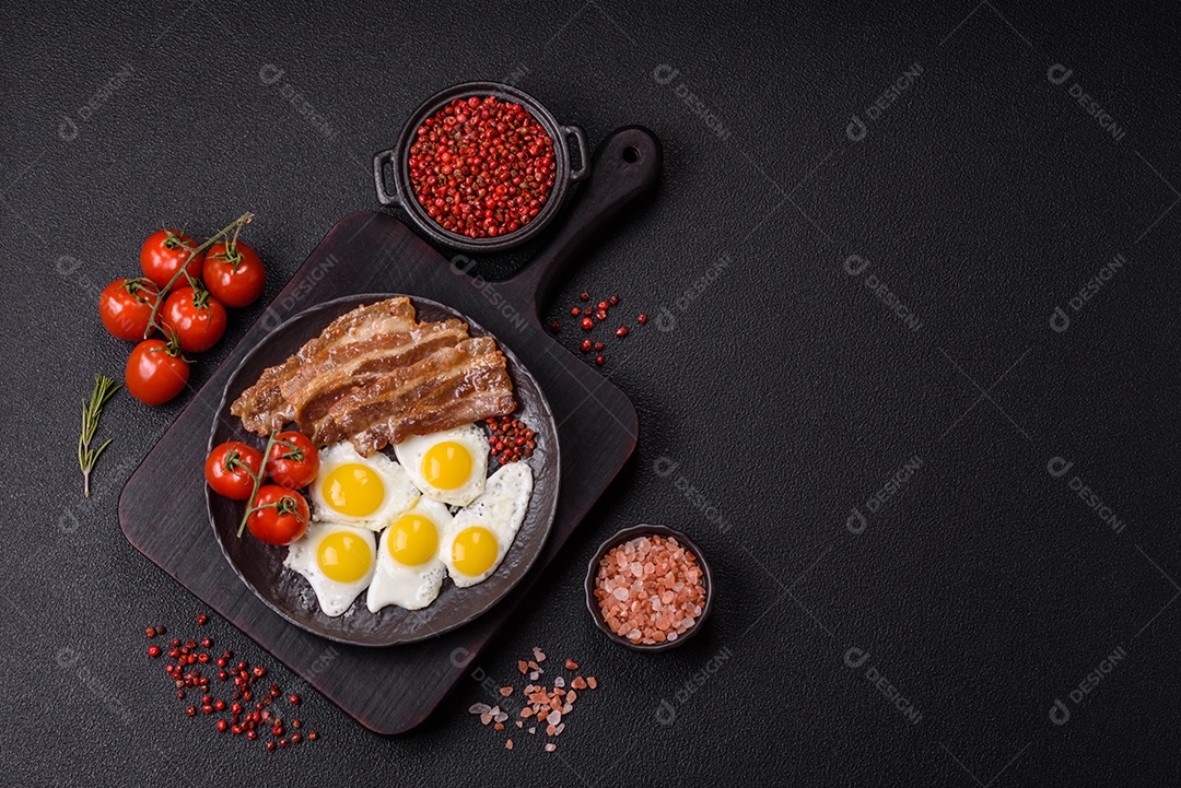 A imagem mostra um café da manhã farto com ovos fritos, bacon e tomates