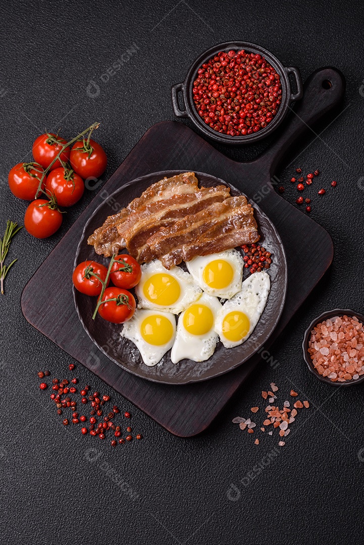 A imagem mostra um café da manhã farto com ovos fritos, bacon e tomates