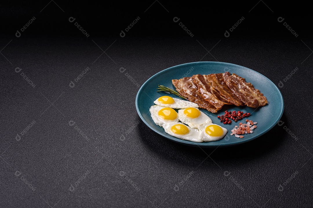 A imagem mostra um café da manhã farto com ovos fritos, bacon e tomates