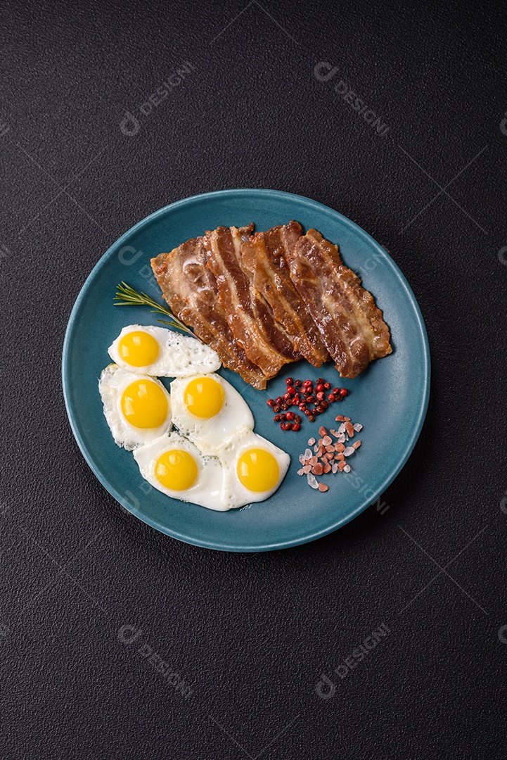 A imagem mostra um café da manhã farto com ovos fritos, bacon e tomates
