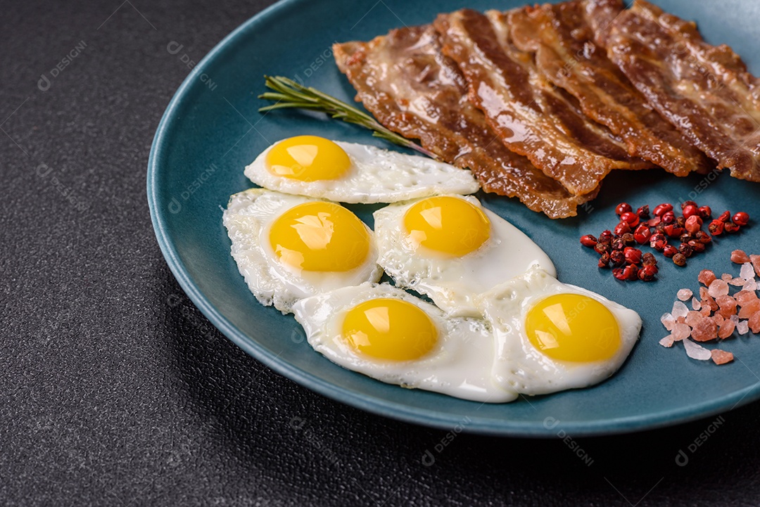 A imagem mostra um café da manhã farto com ovos fritos, bacon e tomates