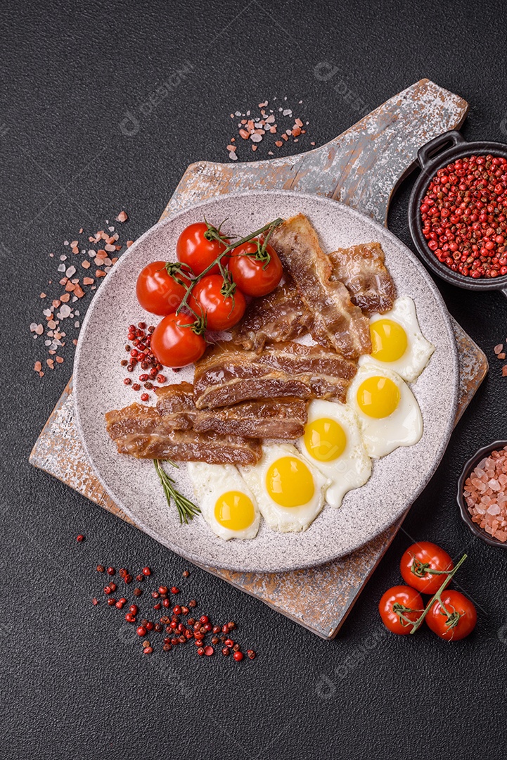 A imagem mostra um café da manhã farto com ovos fritos, bacon e tomates